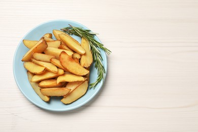 Photo of Plate with delicious baked potatoes and rosemary on white wooden table, top view. Space for text