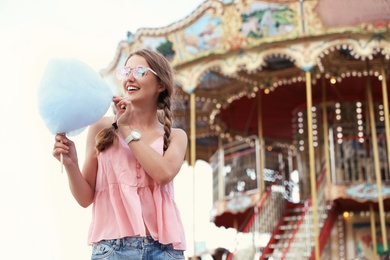 Photo of Young woman with cotton candy in amusement park. Space for text