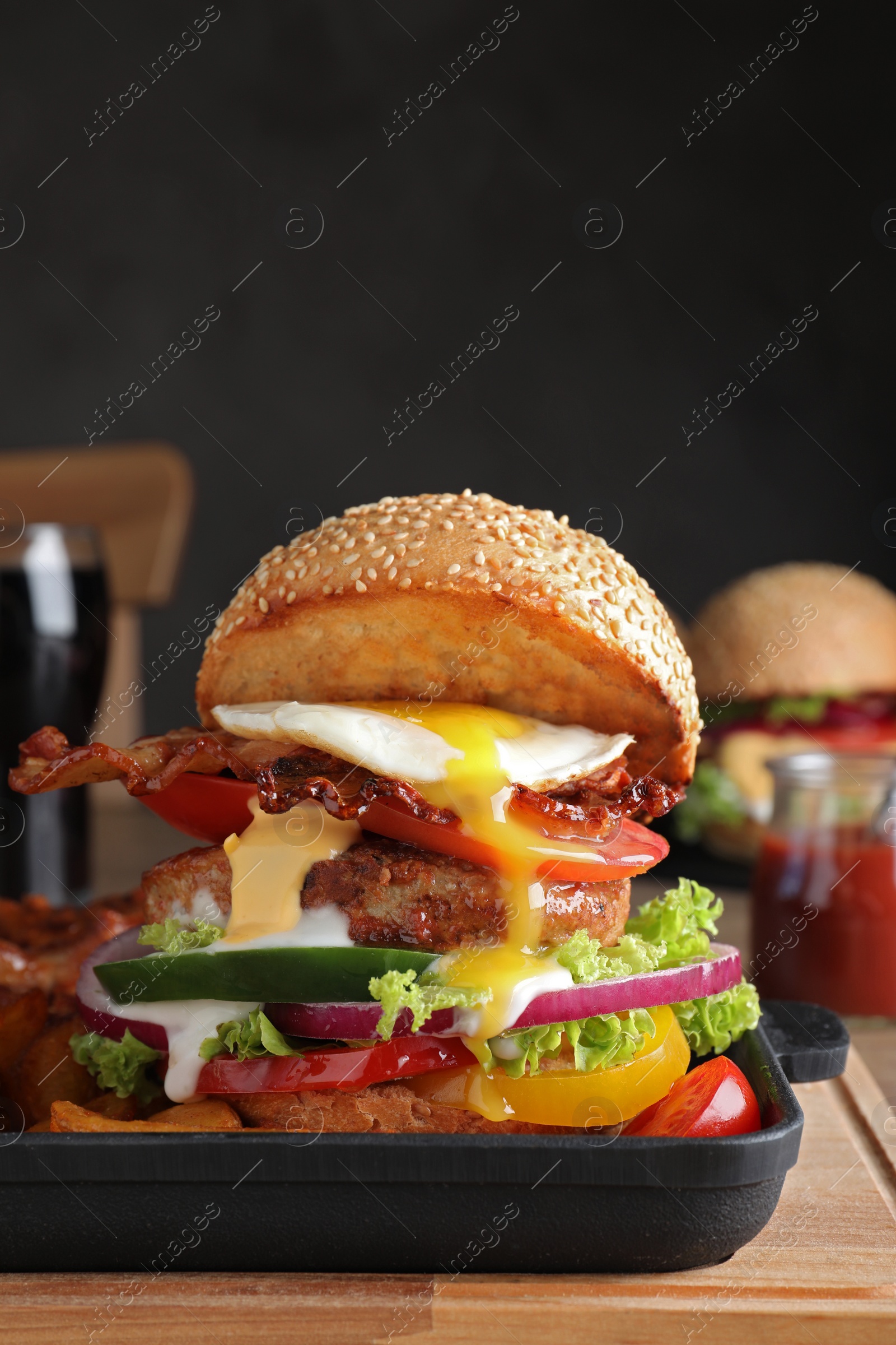 Photo of Serving pan with juicy bacon burger on wooden board