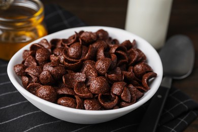 Photo of Breakfast cereal. Chocolate corn flakes in bowl on table, closeup