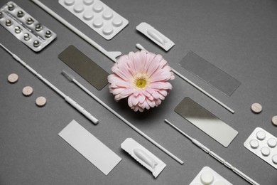 Photo of Many gynecological tools, pills and gerbera flower on grey background, above view