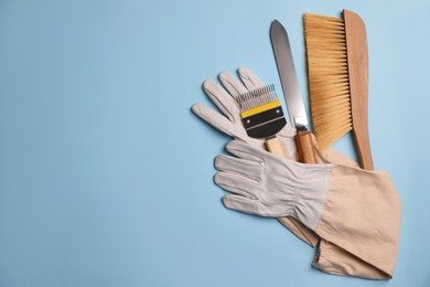 Photo of Beekeeping tools and gloves on light blue background, flat lay. Space for text