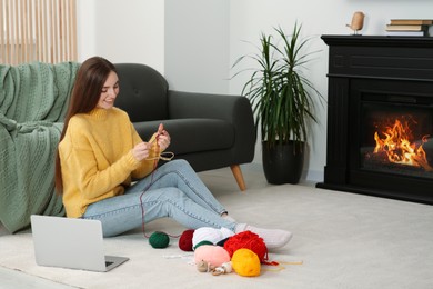 Photo of Young woman learning to knit with online course at home, space for text. Handicraft hobby