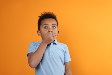 Photo of Emotional African-American boy on orange background. Space for text