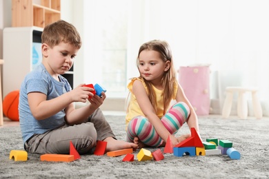 Photo of Little children playing with colorful blocks indoors