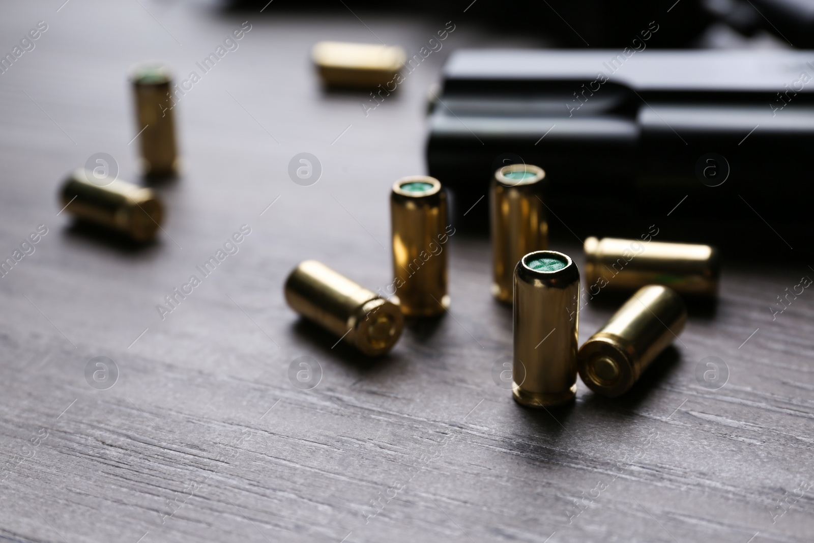 Photo of Pistol bullets on wooden table, closeup. Professional gun