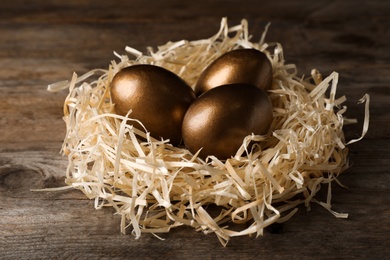 Photo of Nest with golden eggs on wooden background. Pension concept