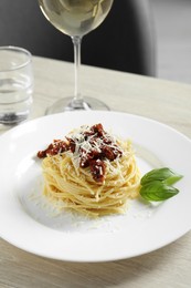 Photo of Tasty spaghetti with sun-dried tomatoes and parmesan cheese served on wooden table, closeup. Exquisite presentation of pasta dish