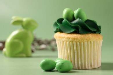 Photo of Tasty cupcake with Easter decor on green background, closeup. Space for text