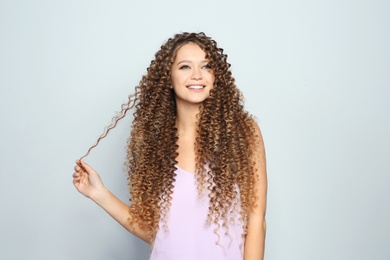 Portrait of beautiful young woman with shiny wavy hair on color background