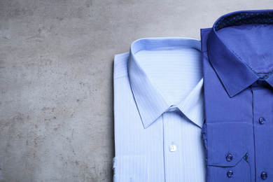 Photo of Stylish shirts on grey background, flat lay. Dry-cleaning service