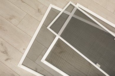 Photo of Set of window screens on wooden floor, flat lay