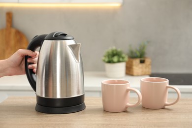 Photo of Woman with electric kettle in kitchen, closeup. Space for text
