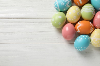 Photo of Many colorful painted Easter eggs on wooden background, top view. Space for text