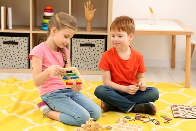 Photo of Children playing with different math game kits on floor in room. Study mathematics with pleasure