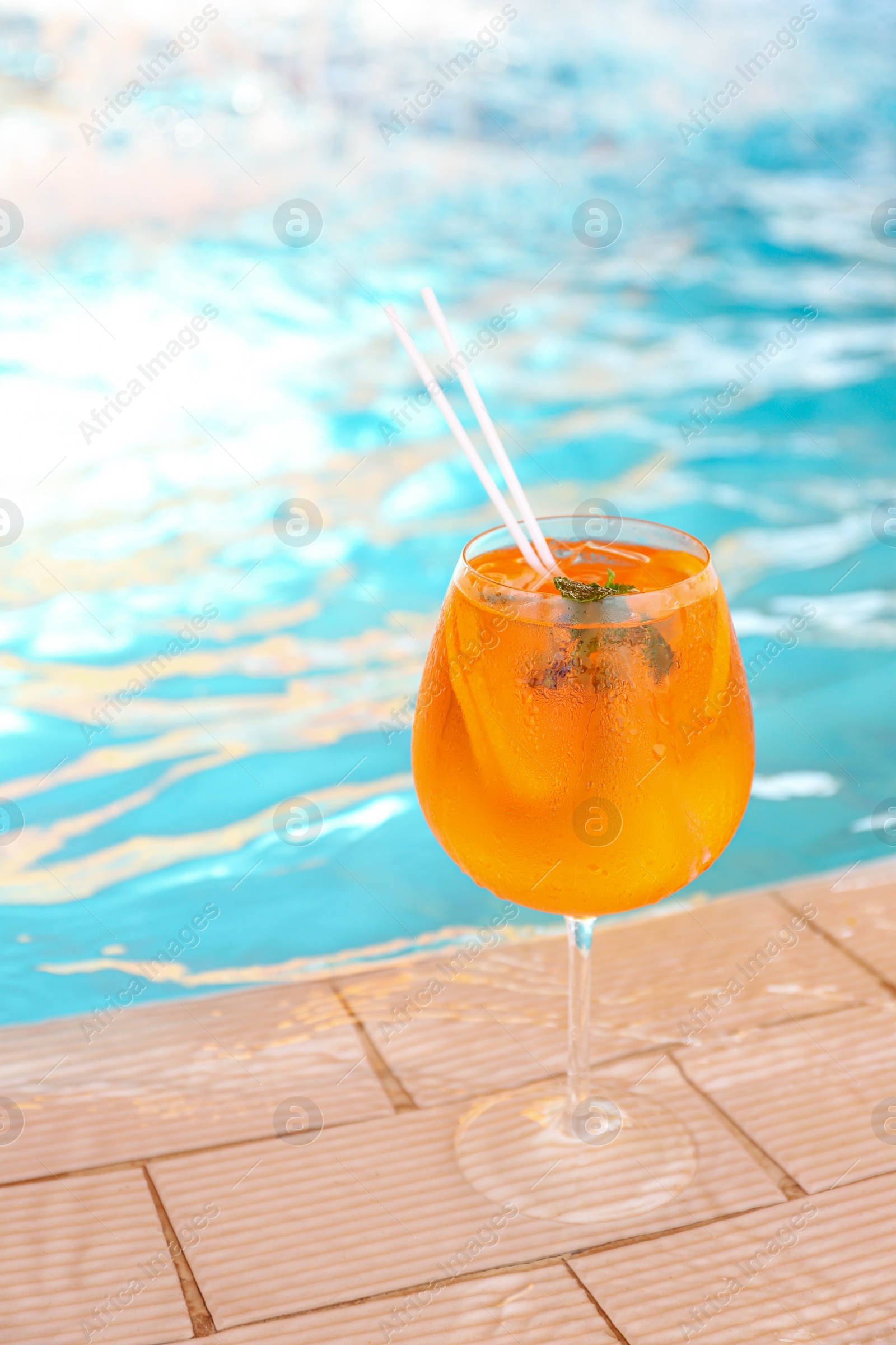 Photo of Glass of delicious cocktail near swimming pool. Refreshing drink