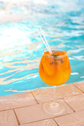 Photo of Glass of delicious cocktail near swimming pool. Refreshing drink
