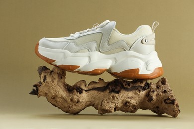 Photo of Stylish presentation of new white sneaker on snag against beige background