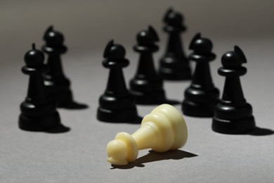 Photo of Black chess pieces and white one on grey background, closeup. Bullying concept