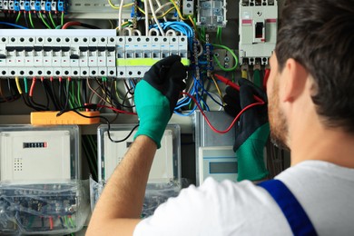 Photo of Electrician checking electric current with multimeter indoors, closeup