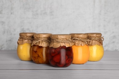 Photo of Jars with canned fruit jams on wooden table