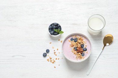 Photo of Bowl of tasty oatmeal with blueberries and yogurt on white wooden table, flat lay. Space for text