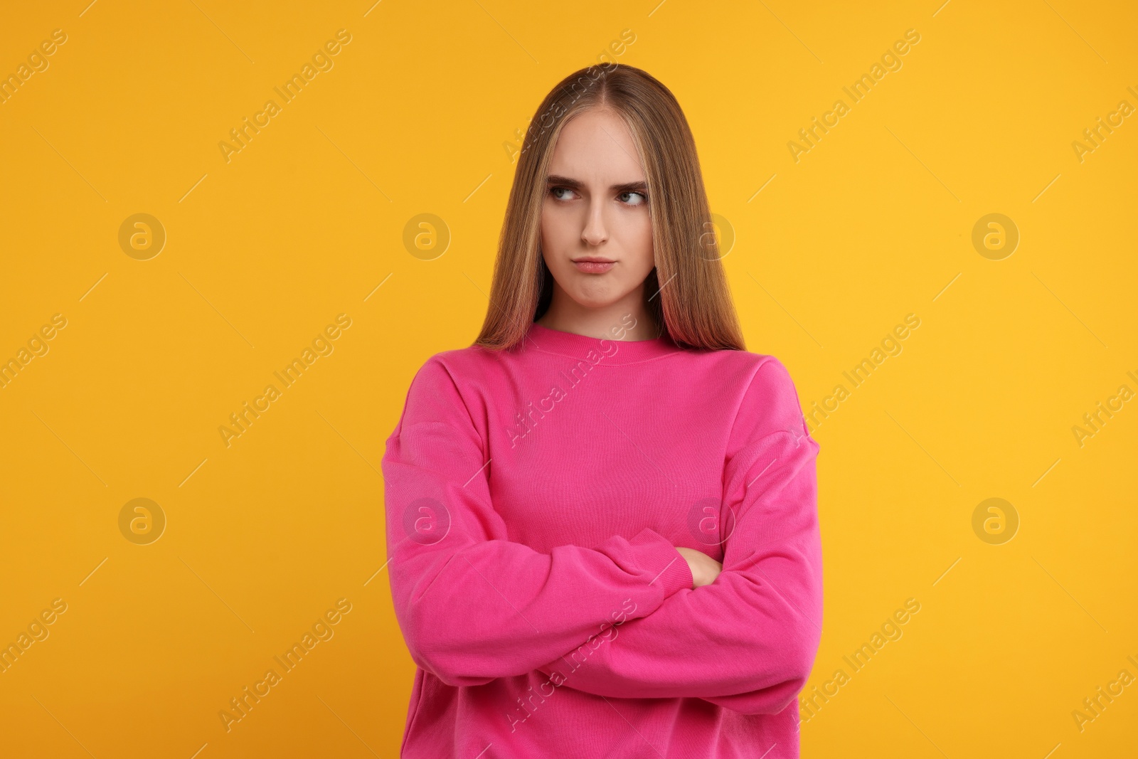 Photo of Resentful woman with crossed arms on orange background
