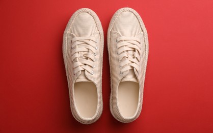 Photo of Pair of stylish comfortable shoes on red background, flat lay