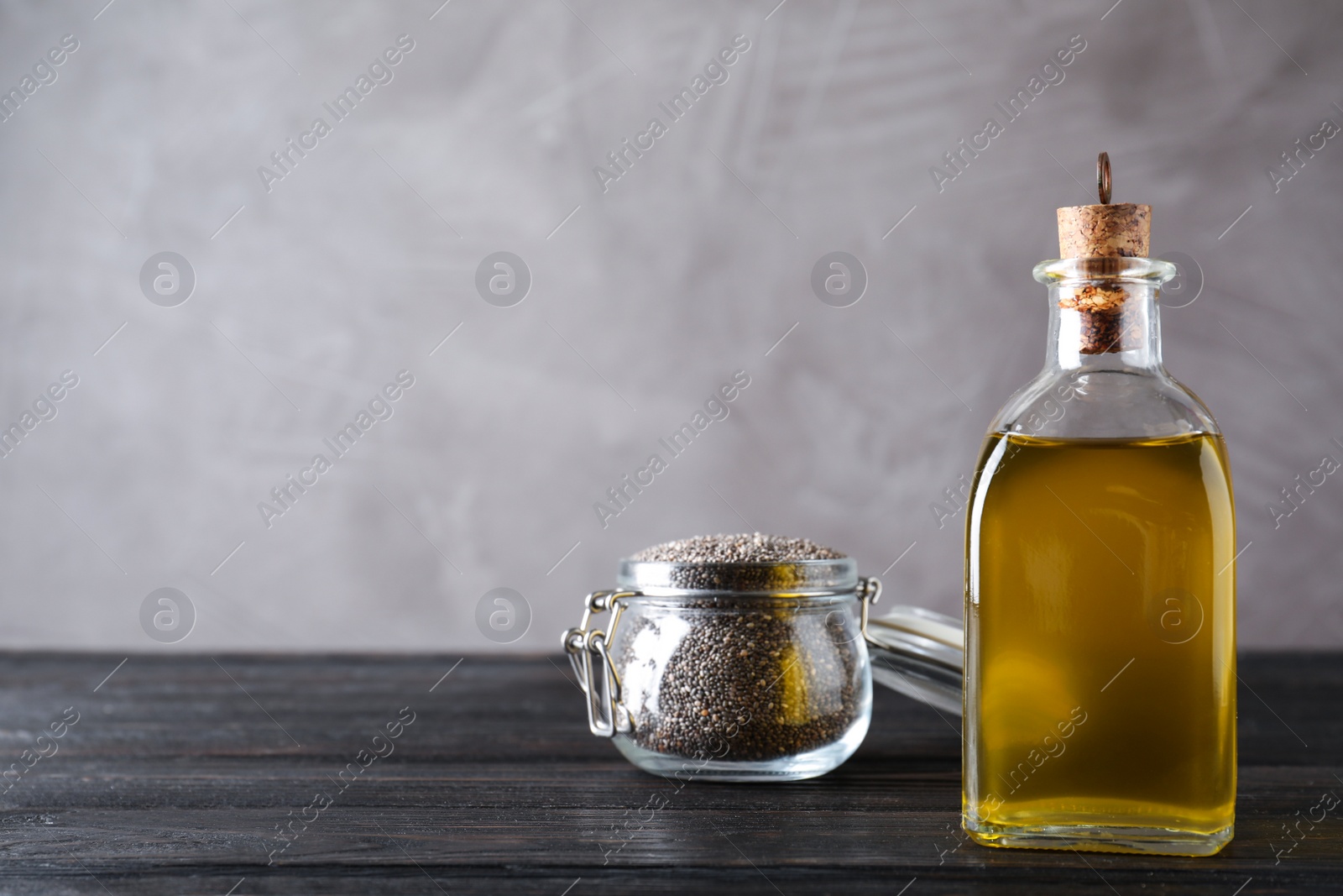 Photo of Bottle of chia oil and jar with seeds on table. Space for text