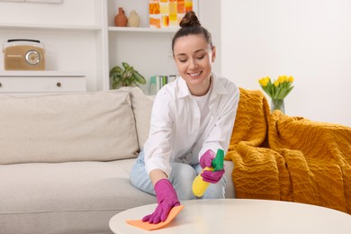 Photo of Spring cleaning. Young woman tidying up living room at home