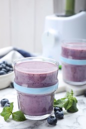 Photo of Tasty blueberry smoothie with mint and fresh berries on white marble table, closeup