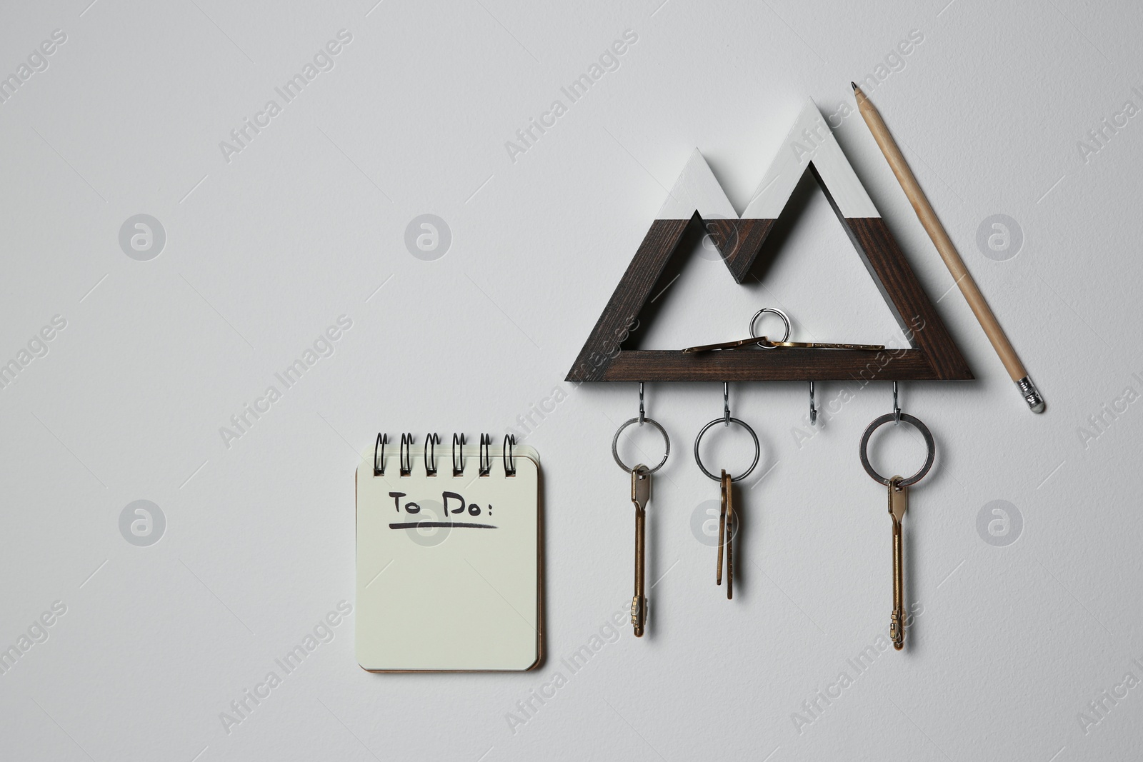 Photo of Wooden key holder and to do list on light grey wall indoors
