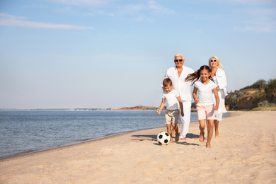 Photo of Cute little children with grandparents spending time together on sea beach