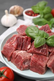 Photo of Cut fresh beef meat with basil leaves on table, closeup