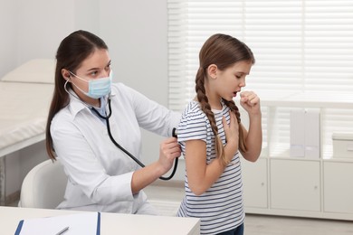 Photo of Doctor examining coughing girl in hospital. Cold symptoms