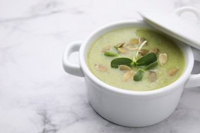 Photo of Delicious broccoli cream soup with pumpkin seeds on white marble table, closeup. Space for text
