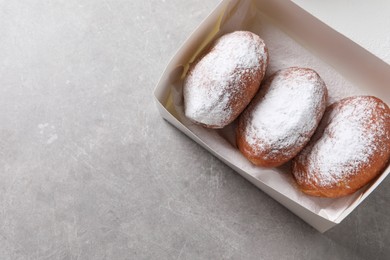 Photo of Delicious sweet buns in box on gray table, top view. Space for text