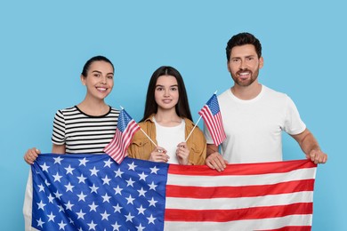 Photo of 4th of July - Independence Day of USA. Happy family with American flags on light blue background