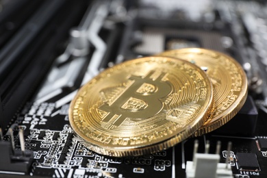 Photo of Golden bitcoins on computer circuit board, closeup. Space for text