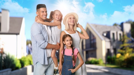 Image of Happy family standing in front of their house on sunny day 
