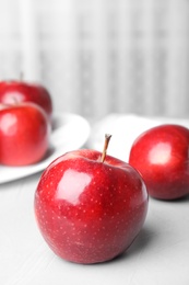 Photo of Ripe juicy red apples on light table indoors