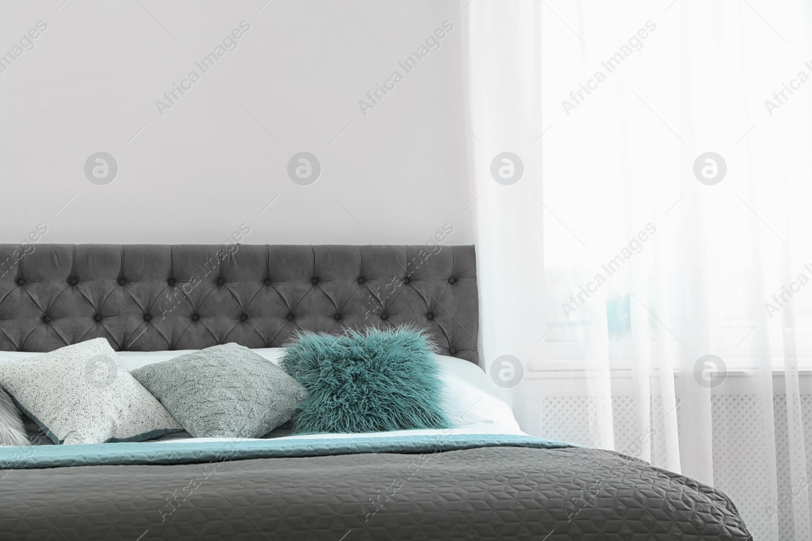 Photo of Cozy bed with different pillows and plaid in light room. Idea for interior decor