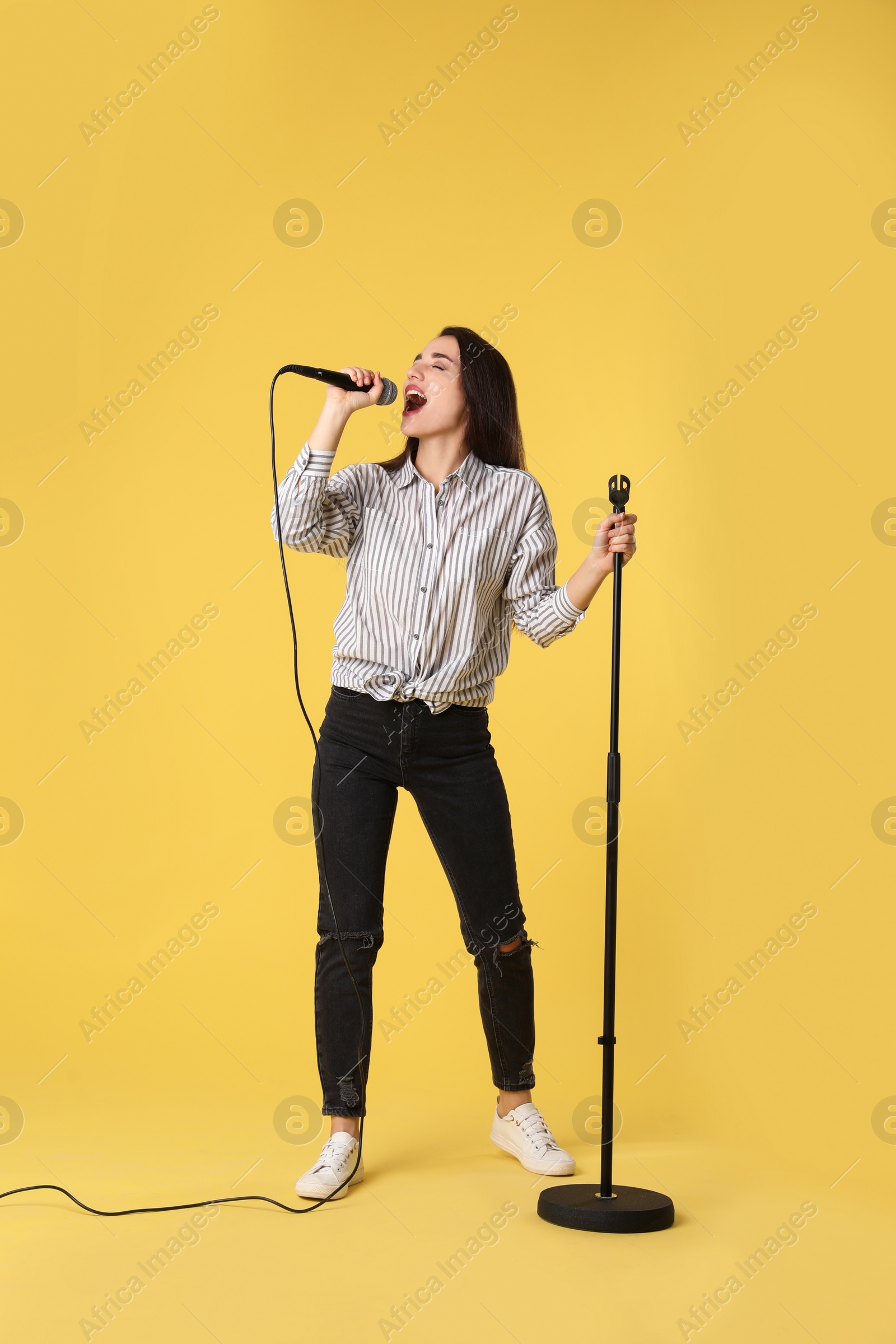 Photo of Young woman wearing casual clothes singing in microphone on color background