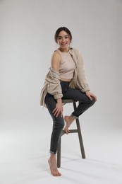 Photo of Portrait of beautiful woman sitting on chair against light grey background