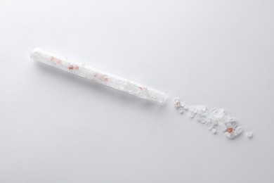Photo of Glass tube with pink himalayan salt on white background, top view