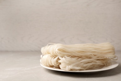Photo of Plate with raw rice noodles on table. Space for text