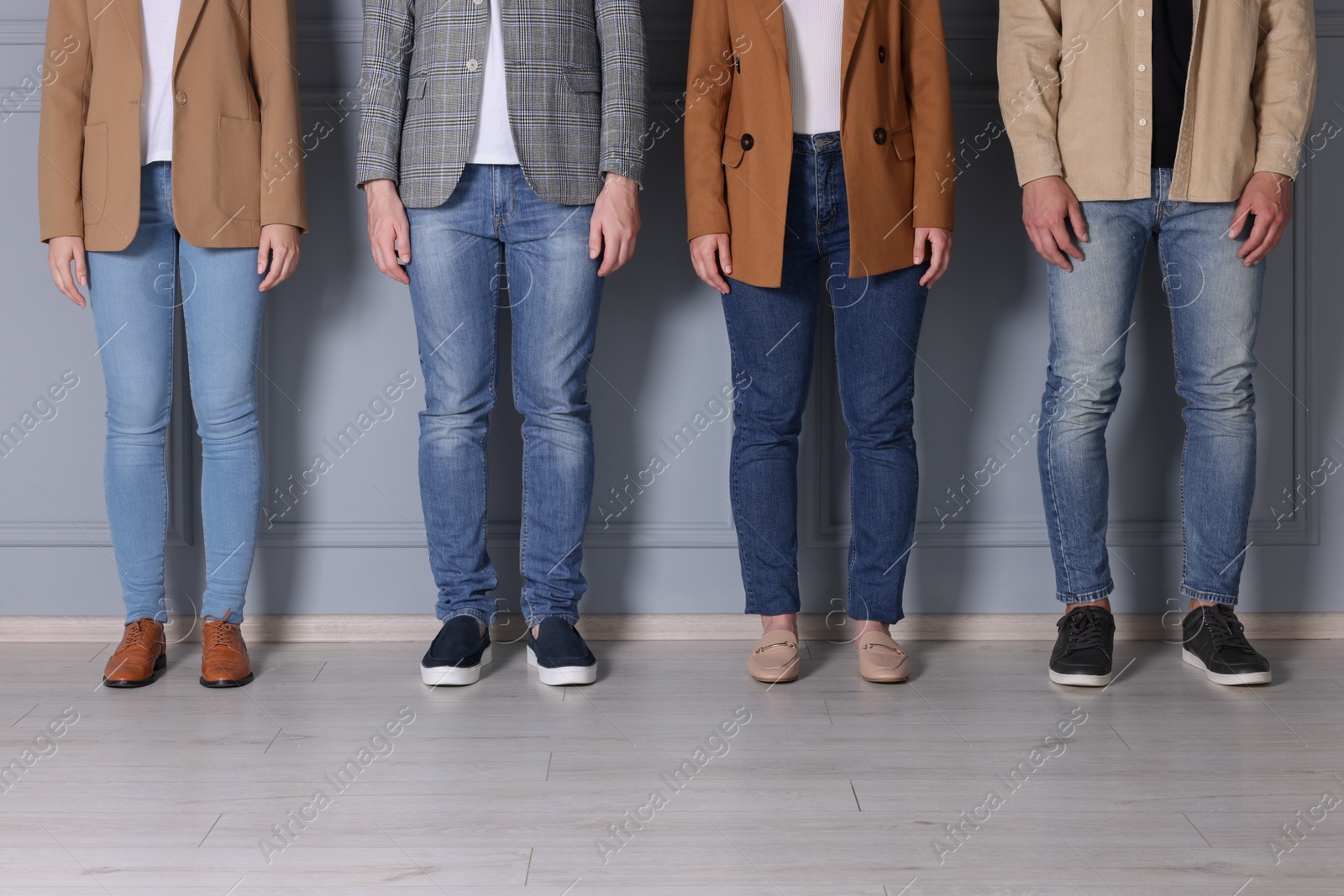 Group of people in stylish jeans near light grey wall indoors, closeup Photo of Group of people in stylish jeans near light grey wall indoors, closeup