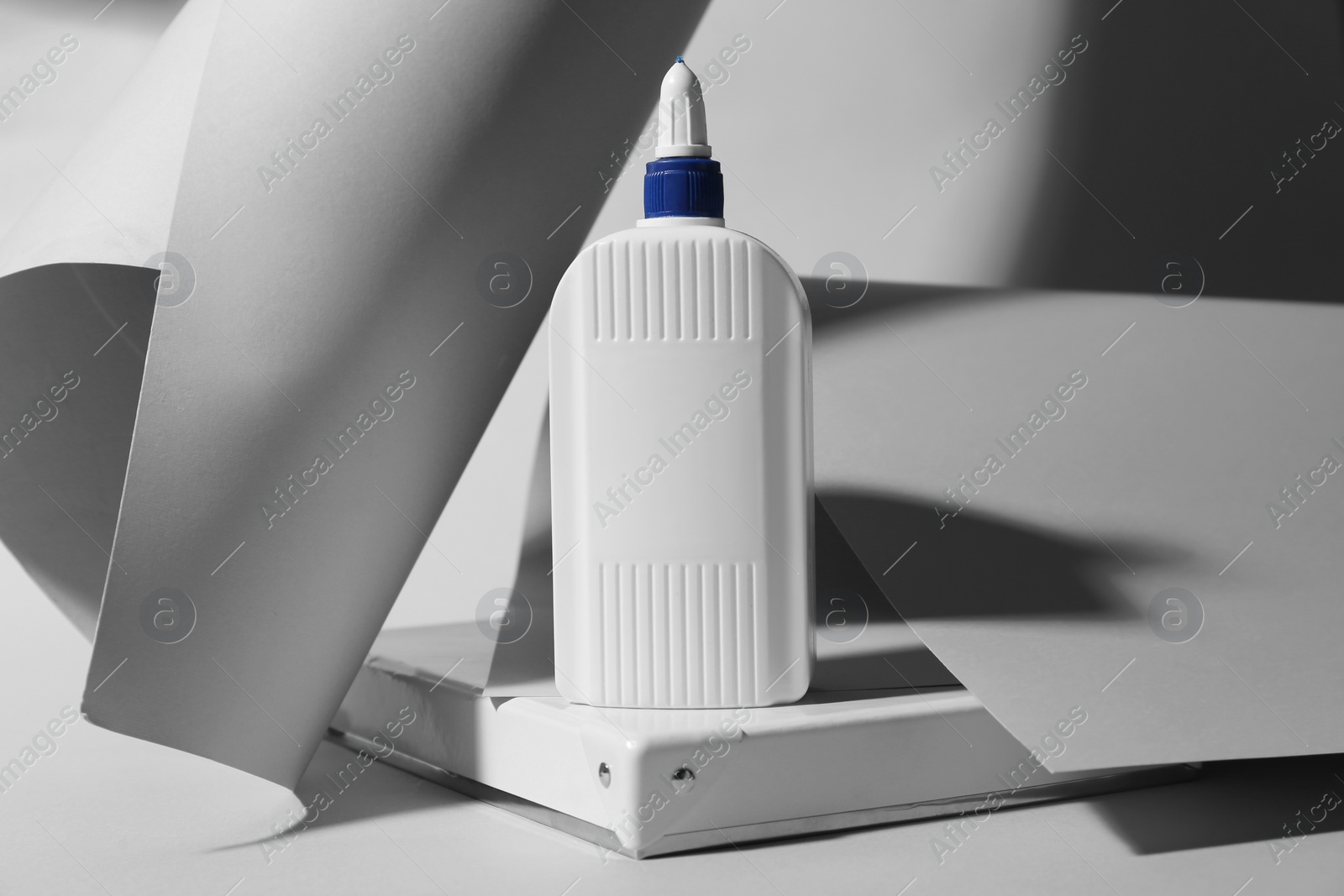 Photo of Bottle of glue and paper on grey background