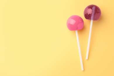 Photo of Tasty lollipops on yellow background, flat lay. Space for text