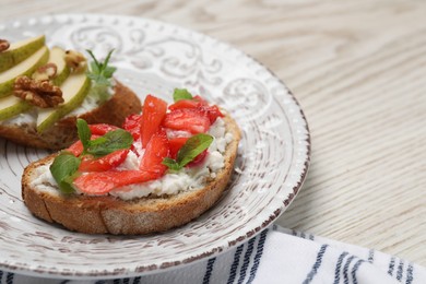 Photo of Delicious bruschettas with fresh ricotta (cream cheese), strawberry, mint and pear on wooden table